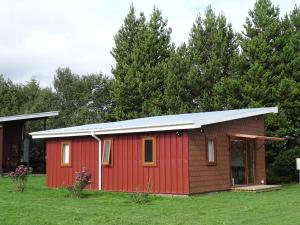 a red shed in a yard with trees at CasaMisur in Puerto Varas