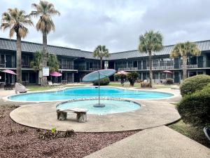a pool with a bench and an umbrella in front of a building at Extended Stay SA in San Antonio