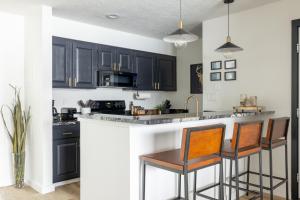 a kitchen with black cabinets and bar stools at Lakeside & MTN View Condo - Pool-Hot Tub-Gym-Sauna in Dillon