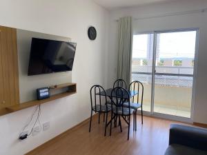 sala de estar con mesa, sillas y TV en Apês Palmeira Dourada - Centro de Palmas e Aromaterapia, en Palmas