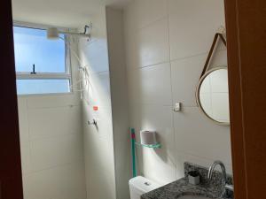 a white bathroom with a sink and a mirror at Apês Palmeira Dourada - Centro de Palmas e Aromaterapia in Palmas