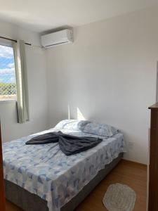 Apês Palmeira Dourada - Centro de Palmas e Aromaterapia في بالماس: سرير مع لحاف أزرق في غرفة مع نافذة