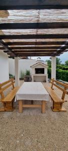 a picnic table and two benches under a roof at Villa Longina in Ljubuški +12 photos