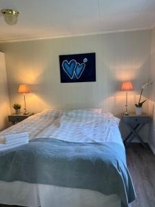 a bedroom with a bed with blue sheets and two lamps at Koselig maritim leilighet sentralt i Stavern in Stavern