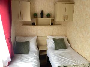 two beds in a small room with cabinets and sidx sidx sidx at 98Lemmington by the beach Ynyslas, Borth in Borth