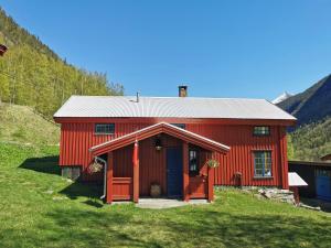 una casa roja con una puerta roja en una colina en Unique farm stay in the steep mountains of Rjukan, en Vemork