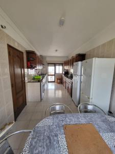 een keuken met een tafel en een witte koelkast bij Margem Sul rooms in Caparica