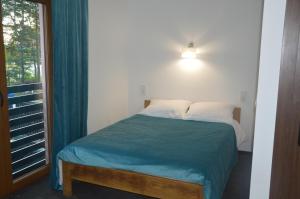 a bedroom with a bed with a blue blanket and a window at Tawerna Nad Sopotem in Susiec