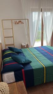 una camera da letto con letto con lenzuola blu e verdi e finestra di Villa Dolce Havana con piscina a Sperlonga