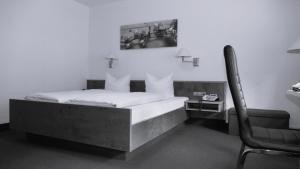 a bedroom with a bed with a chair and a desk at Hotel Sonne in Wolfach