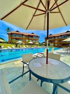 - une table avec un parasol à côté de la piscine dans l'établissement Flat Eco Resort Praia Dos Carneiros, à Praia dos Carneiros