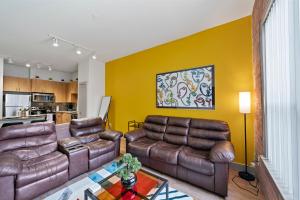 Hot Spot Loft mins from Galleria في هيوستن: غرفة معيشة مع أثاث جلدي بني وجدار أصفر