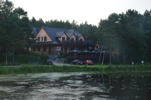 a large house sitting next to a body of water at Tawerna Nad Sopotem in Susiec +4 photos