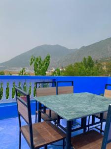 a table and chairs on a balcony with a blue wall at house naim in Chefchaouen