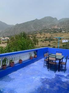 a table and chairs on a blue balcony with mountains at house naim in Chefchaouen