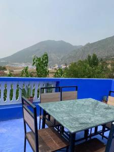 a table and chairs on a balcony with a blue wall at house naim in Chefchaouen