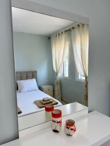 Schlafzimmer mit einem weißen Bett und einem Spiegel in der Unterkunft Apartment for rent Piqeras, Sarande in Piqeras