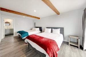 2 letti in una camera con pareti bianche e soffitti in legno di Cape Cod Cottages - Unit 4 a Waldport