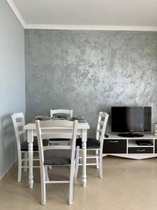 a dining room table with chairs and a tv at Apartment for rent Piqeras, Sarande in Piqeras +24 photos