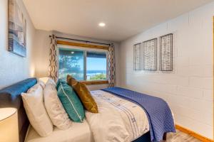 a bedroom with a bed with pillows and a window at Cape Cod Cottages - Unit 8 in Waldport