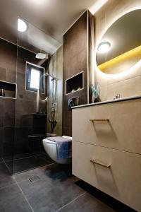 W łazience znajduje się toaleta, umywalka i prysznic. w obiekcie Marimar Panoramic Retreat: Magnificent Space and Breathtaking Gulf View w Kalamácie