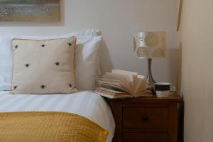 a bed with a lamp and a book on a night stand at The Coachhouse - Cottage with Private Hot tub in Colwyn Bay
