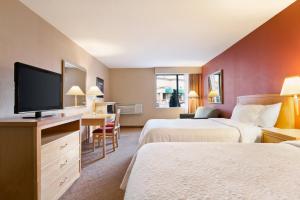 a hotel room with two beds and a flat screen tv at Days Inn by Wyndham Niagara Falls Near The Falls in Niagara Falls