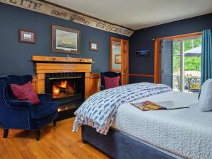 1 dormitorio con chimenea, 1 cama y 1 silla en Abbey's Lantern Hill Inn en Ledyard Center