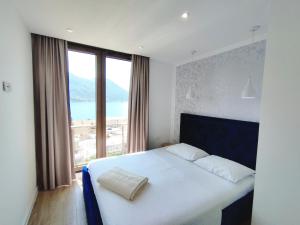 Schlafzimmer mit einem weißen Bett und einem großen Fenster in der Unterkunft Pearl Shell Apartments in Kotor