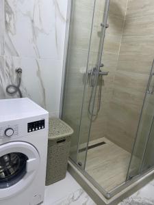 een badkamer met een douche en een wasmachine bij Ellnur Bulevar in Sarajevo