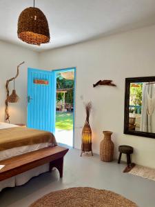 a bedroom with a blue door and a mirror at Pousada Caraíva in Caraíva