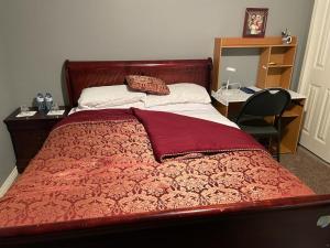 um quarto com uma cama vermelha, uma secretária e uma cadeira. em Steven Abode em Calgary