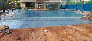 a large swimming pool with blue water and a wooden floor at Two Storey Penthouse with Fantastic View in Manila