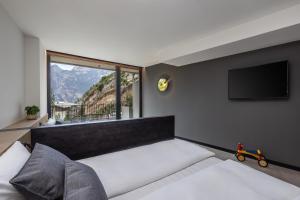 una camera con un grande letto e una TV a schermo piatto di Gardea SoulFamily Resort a Torbole