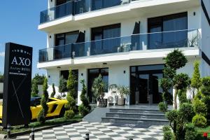 un edificio blanco con un coche amarillo aparcado delante de él en AXO Boutique HOTEL by BUILDING STEFAN en Năvodari