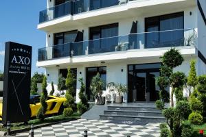 a white building with a yellow car parked in front of it at AXO Boutique HOTEL by BUILDING STEFAN in Năvodari