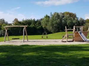 a playground with two swings and a bench in a park at Captivating chalet with a microwave, near the Wadden Sea in Tzummarum