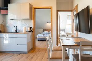 a kitchen and dining room with a table and a bedroom at Ginger Apartament in Wilkasy