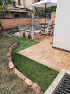 a patio with a bench and an umbrella and grass at Domus Mariposa in Tortolì
