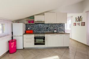 Una cocina con electrodomésticos blancos y un bote de basura rosa. en Luxury villa Cvita, en Radošić
