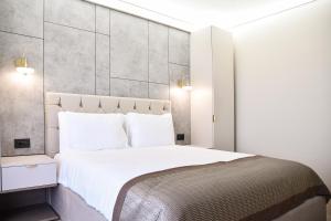 AXO Boutique HOTEL by BUILDING STEFAN في نافوداري: غرفة نوم بسرير ابيض كبير مع مخدات بيضاء