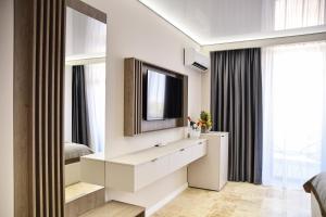 a bedroom with a tv and a white dresser at AXO Boutique HOTEL by BUILDING STEFAN in Năvodari