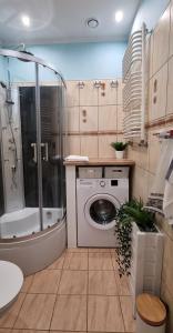 a bathroom with a shower and a washing machine at Apartament Cumulus in Chojna