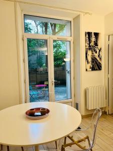 Una mesa y sillas blancas en una habitación con ventana. en Wendy family flat with calm courtyard 3min for metro Paris in 10 mins, en Maisons-Alfort