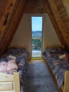 twee bedden in een kamer met een groot raam bij Apartman Andrija in Žabljak