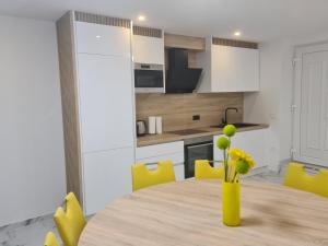 a kitchen with a wooden table and yellow chairs at Apartments Julijana 2 in Privlaka