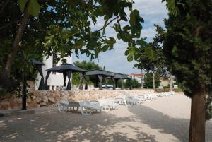 a row of white chairs and umbrellas on a beach at 5 meters FROM THE SEA with private beach - 70m2 Colibri Sunset Apartments in Sveti Petar