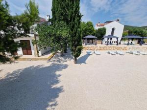 a beach with chairs and trees and a building at 5 meters FROM THE SEA with private beach - 70m2 Colibri Sunset Apartments in Sveti Petar