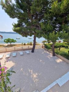 a patio with two trees and chairs and the ocean at 5 meters FROM THE SEA with private beach - 70m2 Colibri Sunset Apartments in Sveti Petar