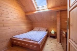 a bed in a wooden room with a window at Domki Piaskowy Raj in Gąski